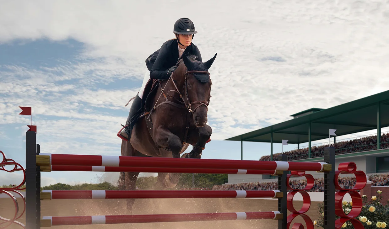 Un cavalier concentré, vêtu de noir, chevauche un cheval puissant et franchit un obstacle rouge et blanc dans une arène bondée par temps nuageux, affichant une détermination sans faille.